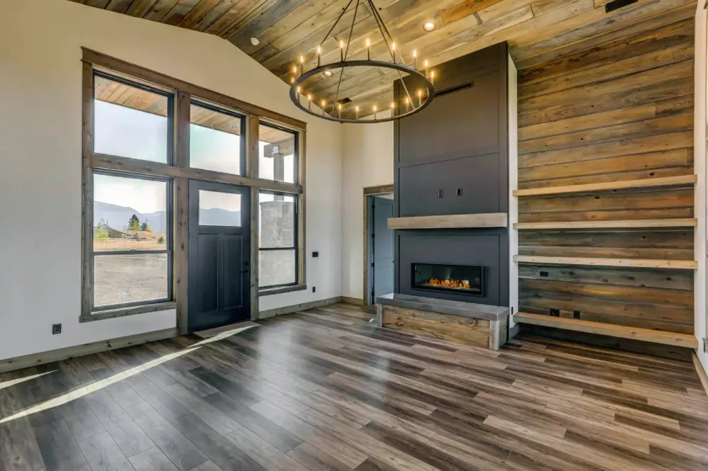 Great room with floor-to-ceiling stone fireplace, vaulted log ceiling, and warm interior lighting